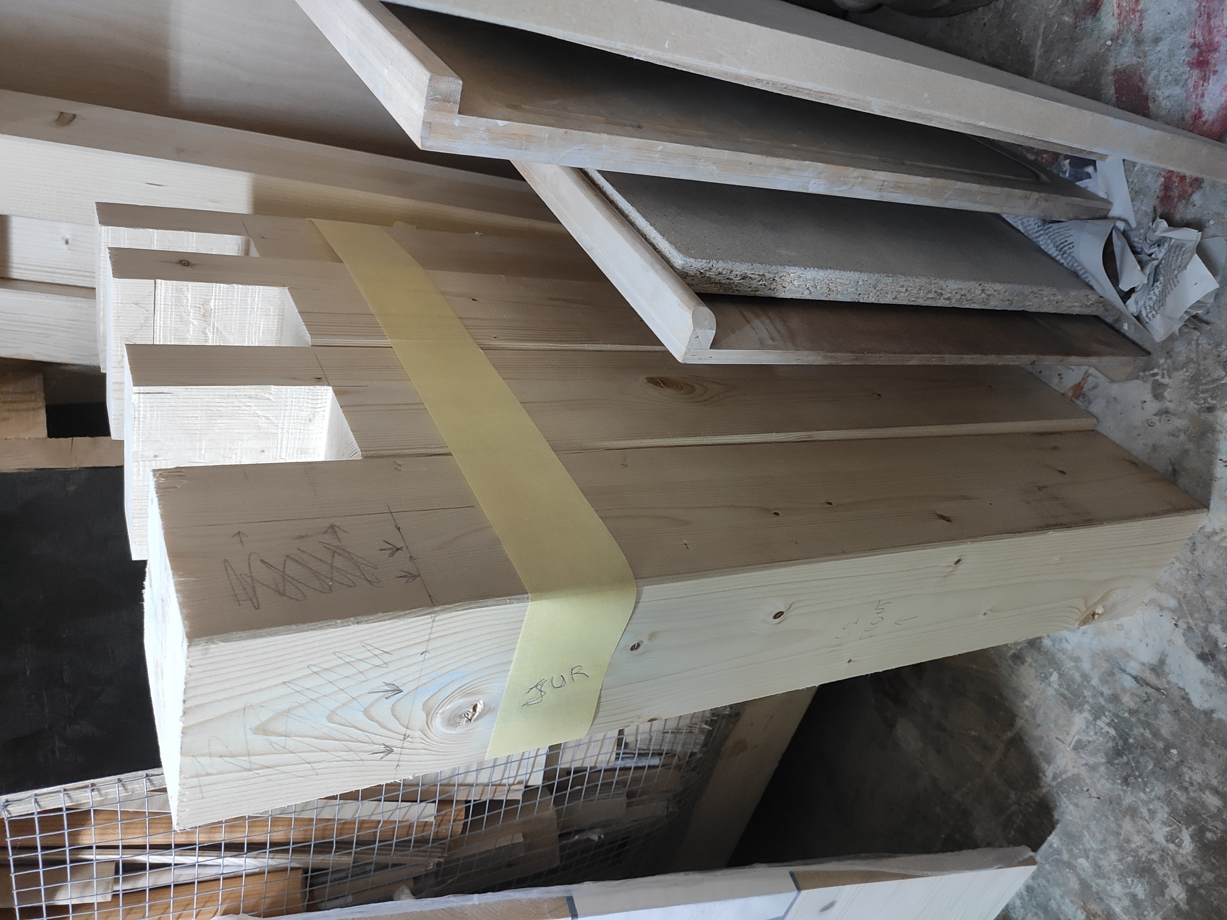 Four thick wooden beams, first has a half-lap joint marked on it, the other three behind it are already cut out.